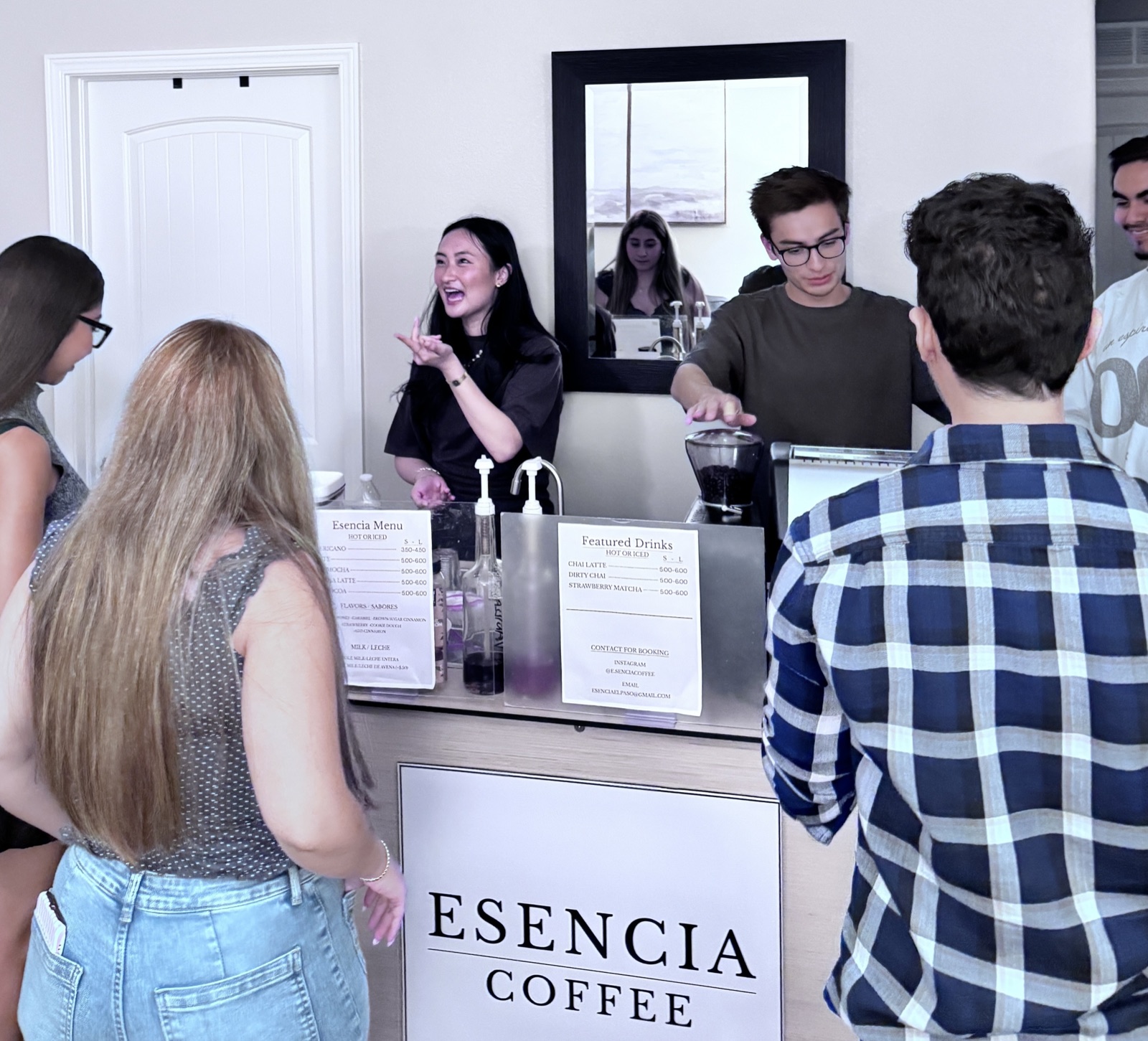Two Esencia Coffee baristas serving drinks to guests at the branded cart